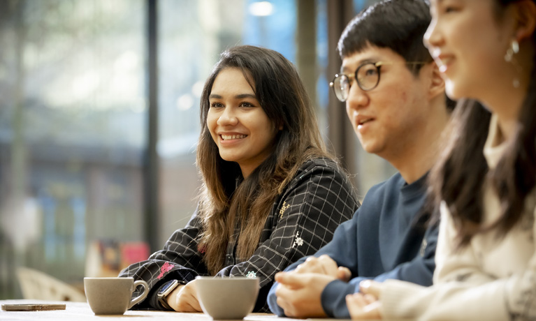 Three international students sitting at a table in The Hub on campus.